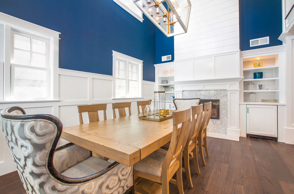 Foto di una sala da pranzo stile marino con pareti blu, parquet scuro, camino classico e cornice del camino piastrellata