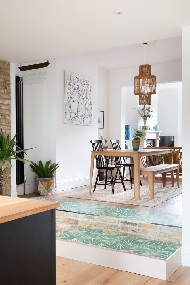 This is an example of a medium sized contemporary open plan dining room in London with white walls, light hardwood flooring, no fireplace and beige floors.