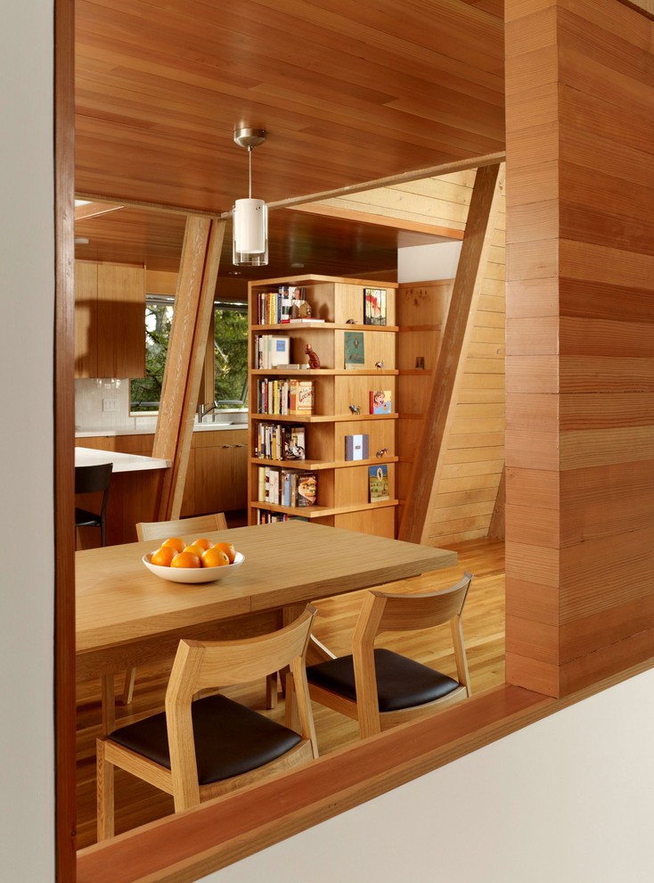 Immagine di una sala da pranzo aperta verso la cucina moderna con pavimento in legno massello medio