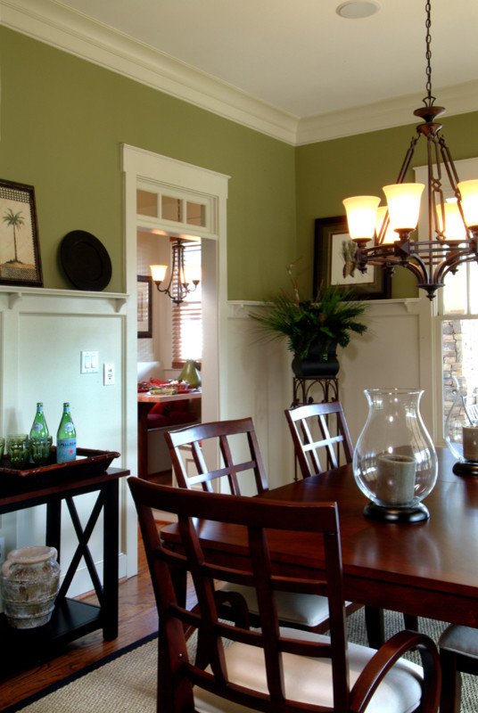 Immagine di una sala da pranzo aperta verso la cucina tradizionale con pareti verdi, pavimento in legno massello medio, nessun camino e pavimento marrone