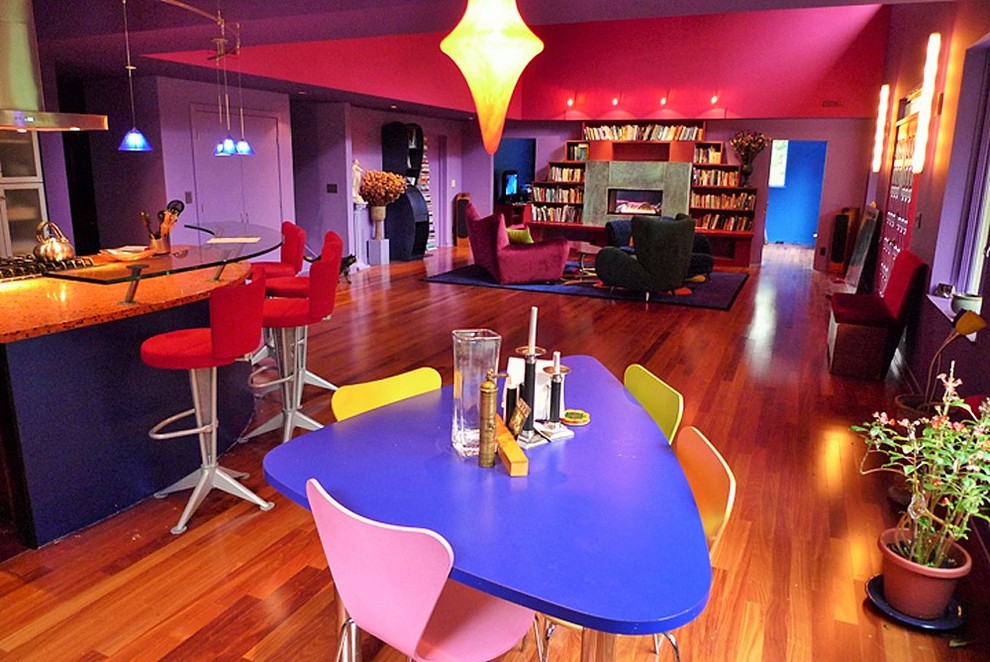 Exemple d'une salle à manger ouverte sur le salon éclectique de taille moyenne avec un mur violet, un sol en bois brun et une cheminée ribbon.
