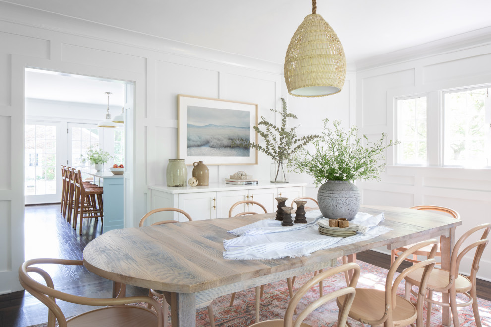 This is an example of a beach style dining room in New York with white walls, dark hardwood flooring, brown floors and panelled walls.