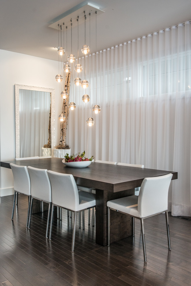 This is an example of a contemporary dining room in Calgary with white walls and dark hardwood flooring.