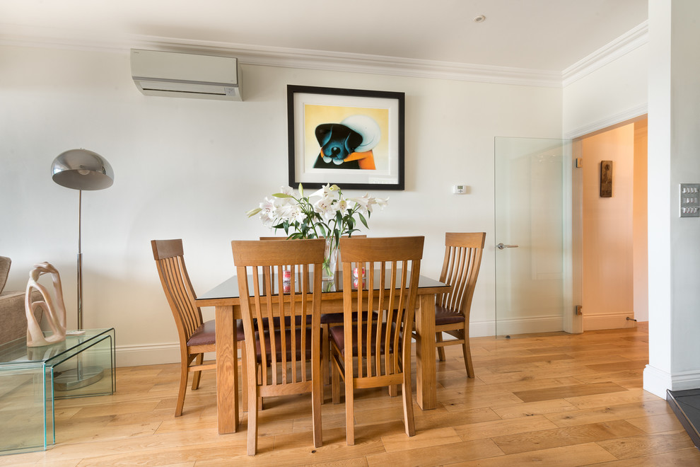 Small contemporary open plan dining room in Devon with white walls and light hardwood flooring.