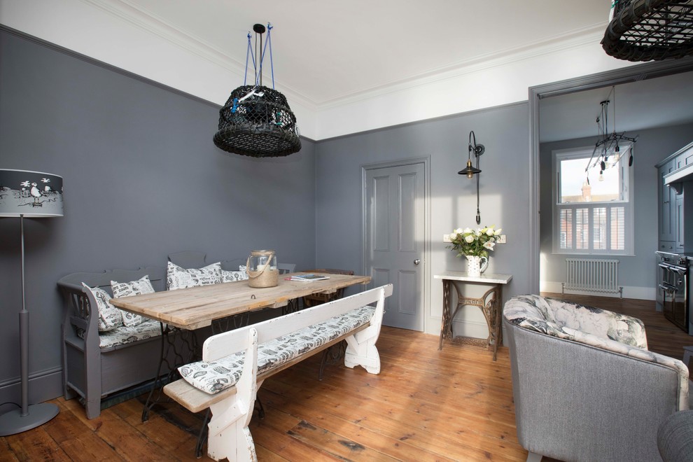 Cette photo montre une grande salle à manger ouverte sur le salon romantique avec un mur gris, un sol en bois brun, un sol marron, une cheminée standard et un manteau de cheminée en métal.