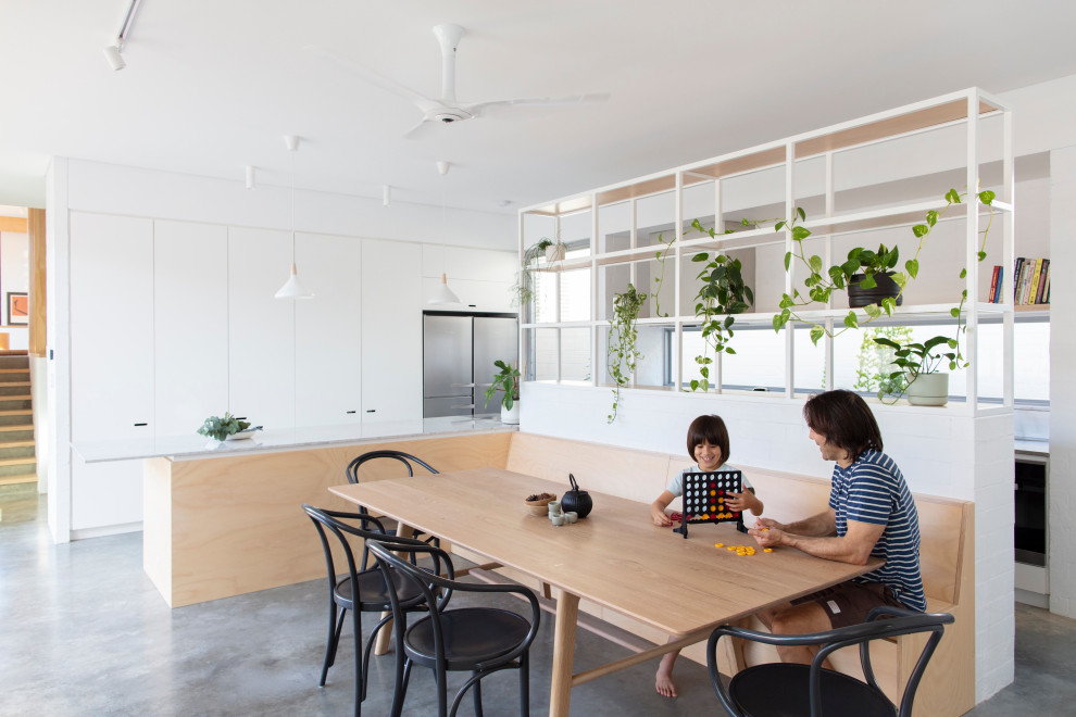 Idee per un angolo colazione industriale con pareti bianche, pavimento in cemento e pavimento grigio