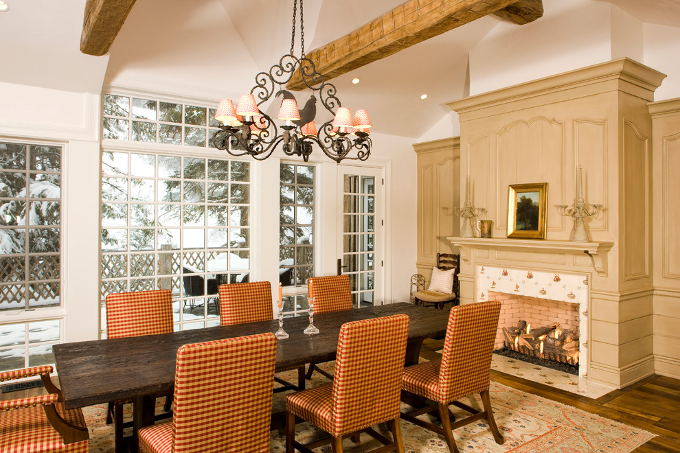 Exemple d'une salle à manger chic avec un mur blanc, parquet foncé, une cheminée standard et un manteau de cheminée en carrelage.