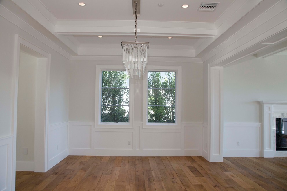 Immagine di un'ampia sala da pranzo aperta verso il soggiorno stile marinaro con pareti bianche e pavimento in legno massello medio