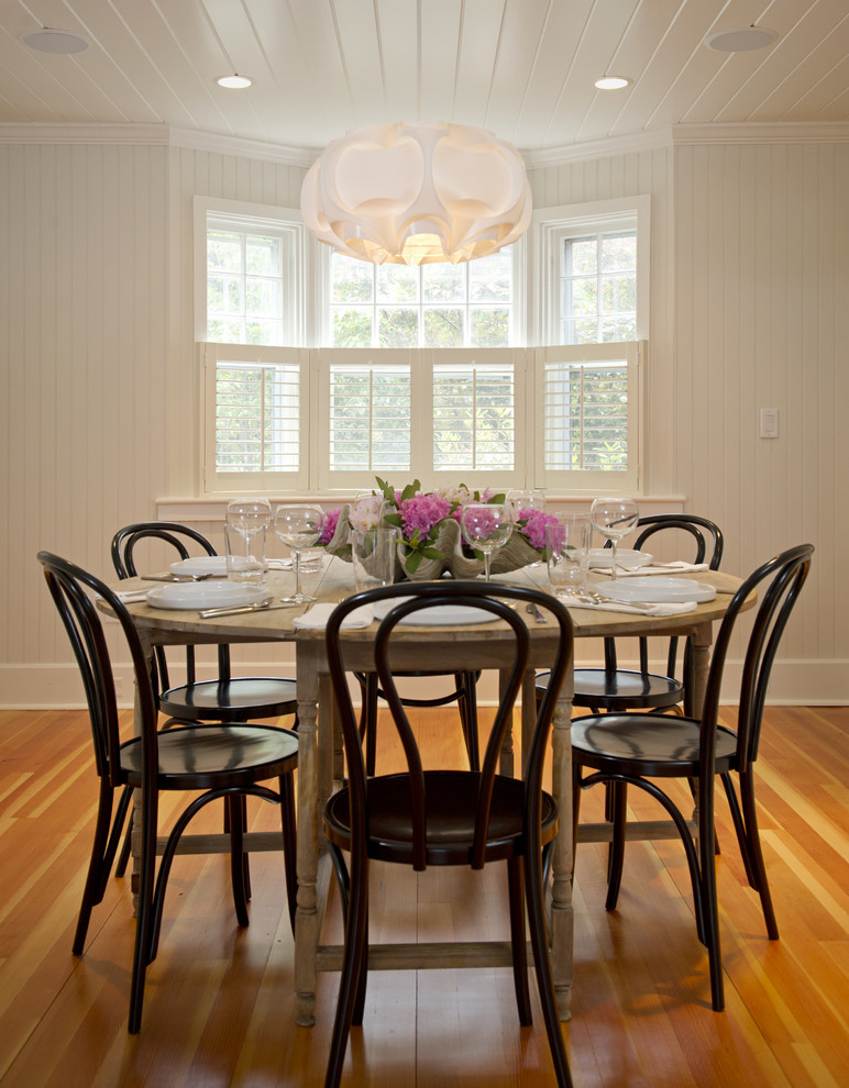 Cette image montre une salle à manger chalet de taille moyenne avec un mur blanc, un sol en bois brun et aucune cheminée.