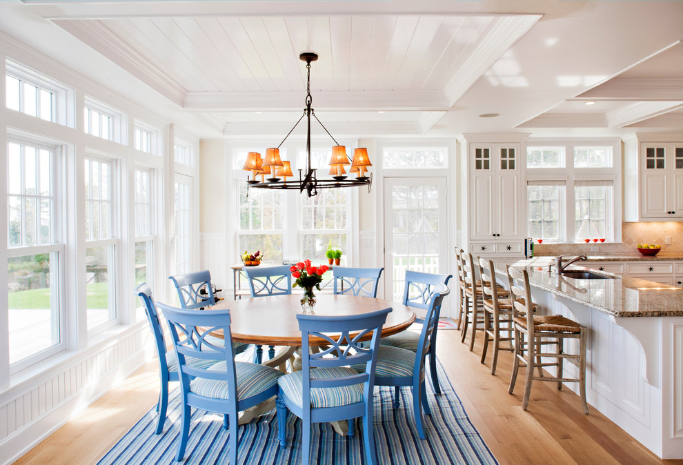 Beach style kitchen/dining room in Boston with white walls and light hardwood flooring.