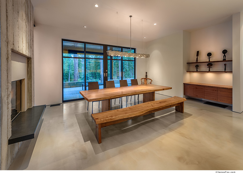 На фото: столовая среднего размера в стиле модернизм с серыми стенами, бетонным полом и фасадом камина из бетона с