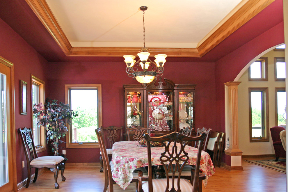 Immagine di una grande sala da pranzo aperta verso il soggiorno classica con pareti rosse, pavimento in legno massello medio e nessun camino