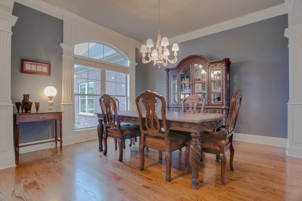 Cette photo montre une très grande salle à manger ouverte sur la cuisine tendance avec un mur gris et un sol en bois brun.