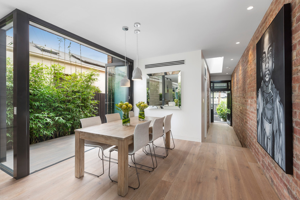 Modernes Esszimmer ohne Kamin mit hellem Holzboden und weißer Wandfarbe in Melbourne