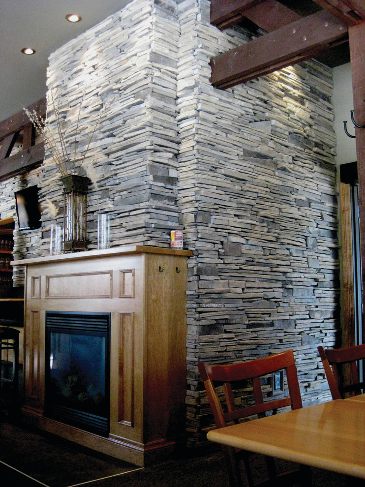 Aménagement d'une salle à manger ouverte sur la cuisine montagne avec une cheminée standard et un manteau de cheminée en pierre.