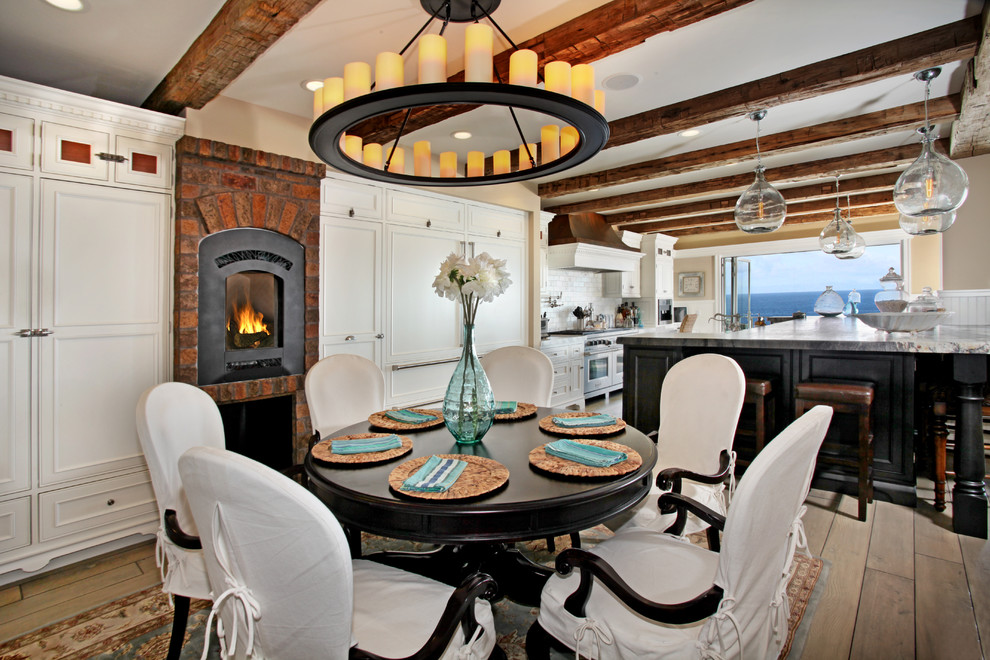 Réalisation d'une salle à manger ouverte sur la cuisine marine avec un sol en bois brun, un manteau de cheminée en brique et un poêle à bois.