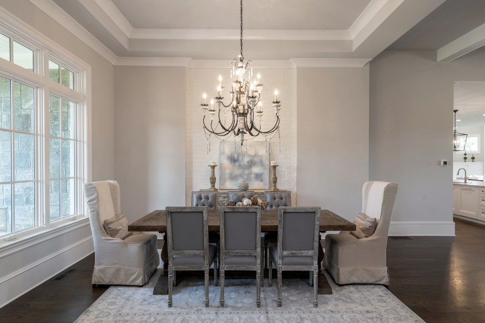 Immagine di una grande sala da pranzo aperta verso il soggiorno classica con pareti grigie, parquet scuro e pavimento marrone