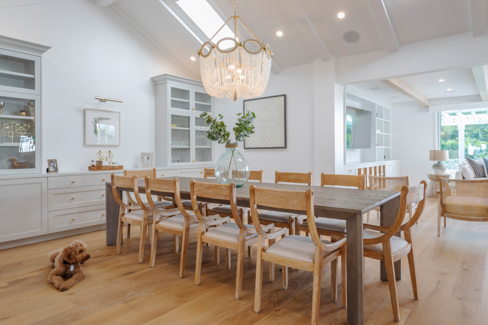 Aménagement d'une grande salle à manger ouverte sur le salon bord de mer avec un mur blanc, un sol en bois brun et un sol beige.