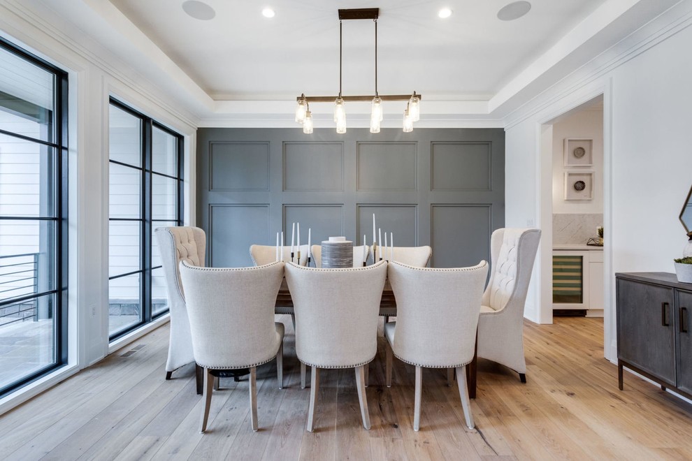 This is an example of a rural enclosed dining room in DC Metro with grey walls, light hardwood flooring, no fireplace, beige floors and a feature wall.