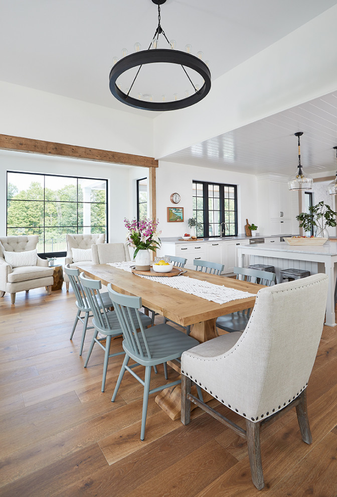 Idée de décoration pour une salle à manger ouverte sur la cuisine champêtre avec un mur blanc, un sol marron et un sol en bois brun.