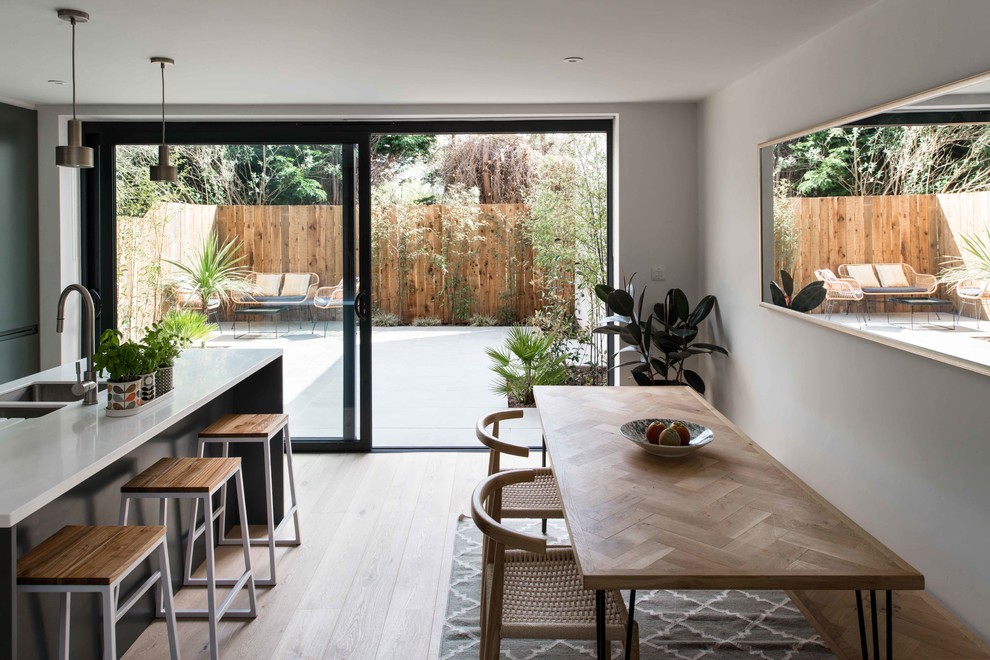 Mittelgroße Moderne Wohnküche ohne Kamin mit hellem Holzboden, weißer Wandfarbe und beigem Boden in London