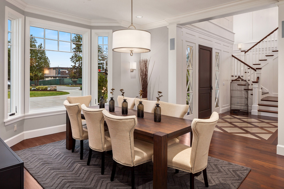 Aménagement d'une salle à manger ouverte sur le salon classique avec un mur blanc, parquet foncé et un sol marron.