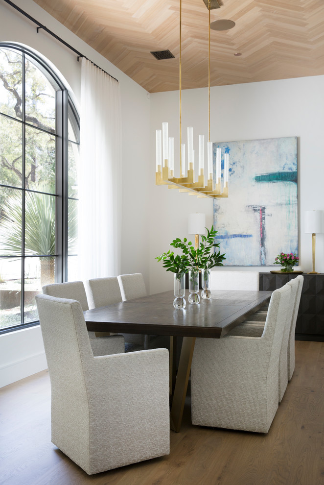 Inspiration for a mediterranean dining room in Austin with white walls, light hardwood flooring, no fireplace and feature lighting.