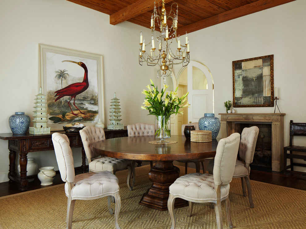 Example of a tuscan medium tone wood floor enclosed dining room design in Miami with beige walls, a standard fireplace and a stone fireplace