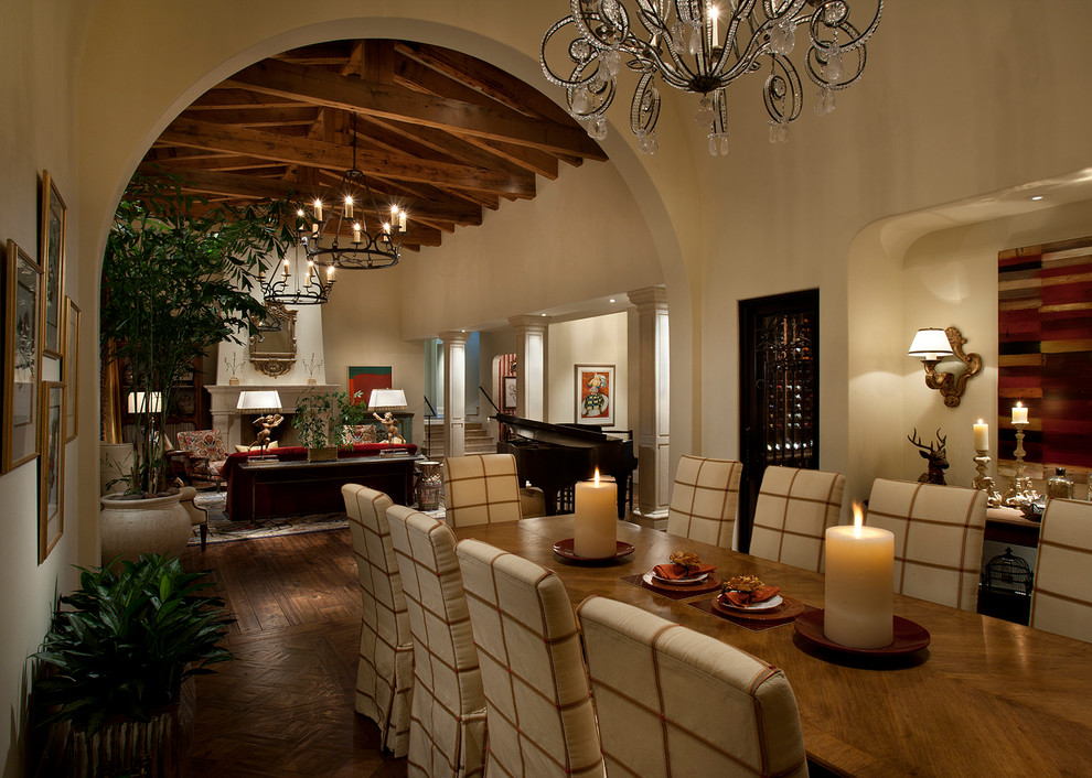 Medium sized mediterranean open plan dining room in Phoenix with beige walls, dark hardwood flooring, a standard fireplace, a stone fireplace surround and feature lighting.