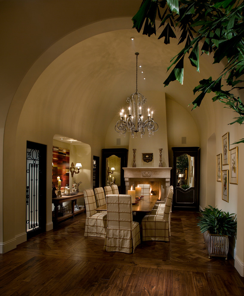 Ispirazione per una sala da pranzo mediterranea chiusa e di medie dimensioni con pareti beige, pavimento in legno massello medio, camino classico e cornice del camino in pietra