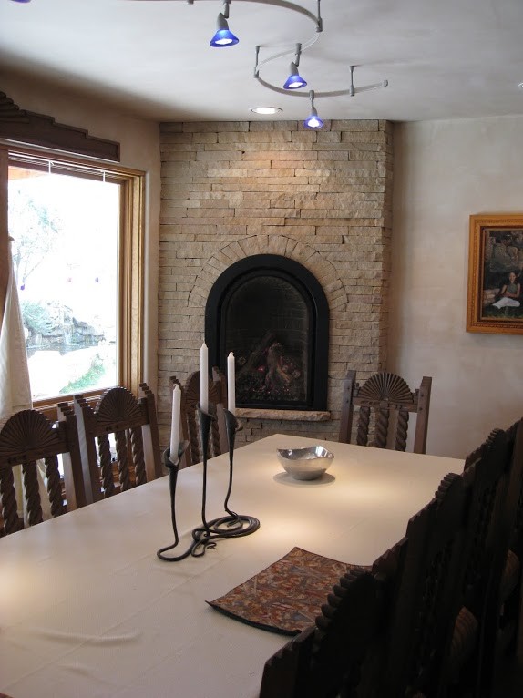 アルバカーキにあるサンタフェスタイルのおしゃれなダイニングキッチン (ベージュの壁、コーナー設置型暖炉、石材の暖炉まわり) の写真