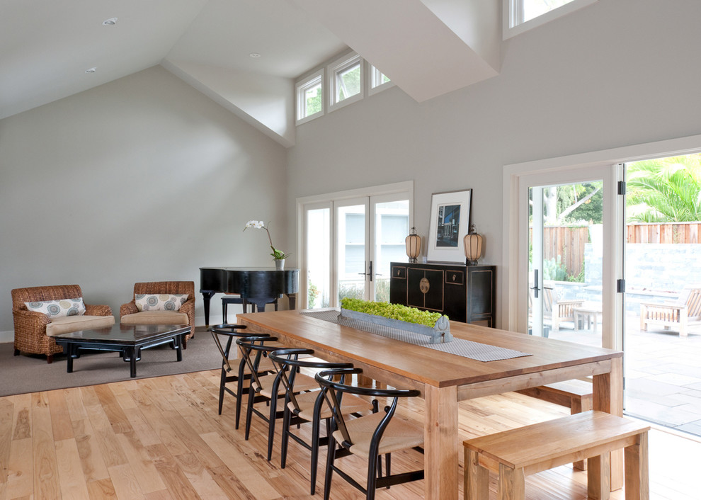 Cette photo montre une salle à manger ouverte sur le salon tendance avec un mur gris, un sol en bois brun et aucune cheminée.