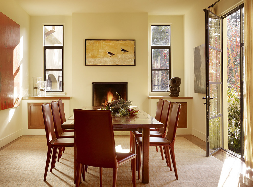 Exemple d'une salle à manger chic avec un mur beige, un sol en bois brun et une cheminée standard.
