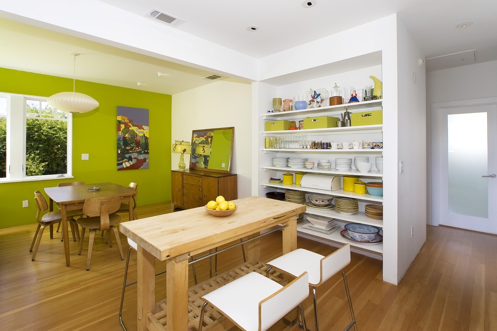 Aménagement d'une salle à manger contemporaine avec un mur vert et un sol en bois brun.