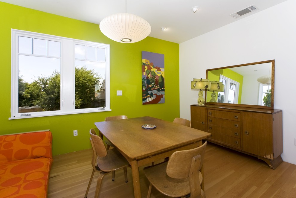 Cette image montre une salle à manger vintage avec un mur vert, un sol en bois brun et éclairage.