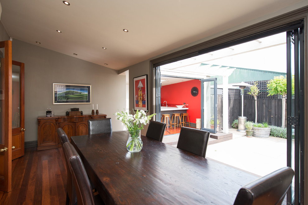 Aménagement d'une salle à manger contemporaine fermée avec un mur gris et un sol en bois brun.
