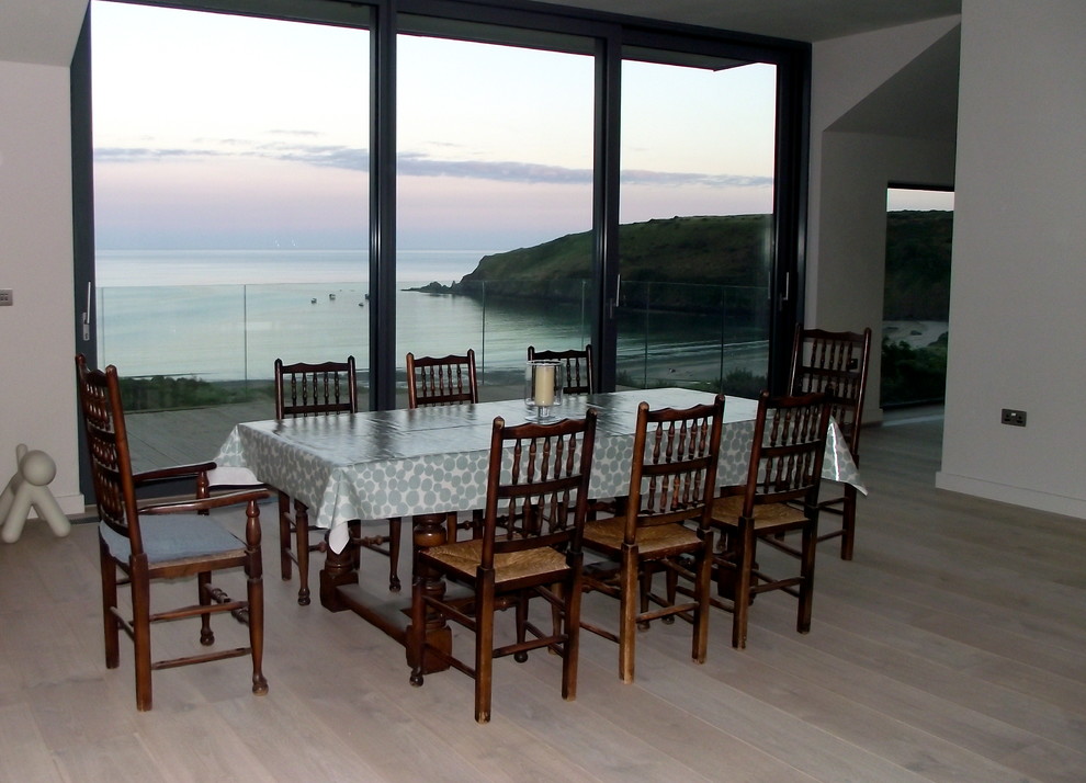Foto di una grande sala da pranzo aperta verso la cucina stile marinaro con pareti grigie e parquet chiaro