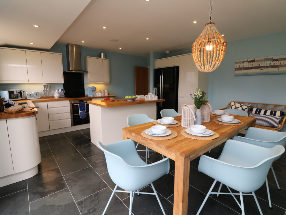 Ispirazione per una sala da pranzo aperta verso la cucina costiera di medie dimensioni con pareti blu, pavimento con piastrelle in ceramica e pavimento grigio