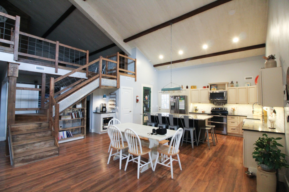 Cette image montre une salle à manger ouverte sur le salon rustique de taille moyenne avec un mur gris, un sol en bois brun, aucune cheminée et un sol marron.