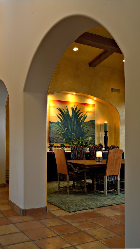 Aménagement d'une très grande salle à manger ouverte sur le salon sud-ouest américain avec un mur jaune et tomettes au sol.