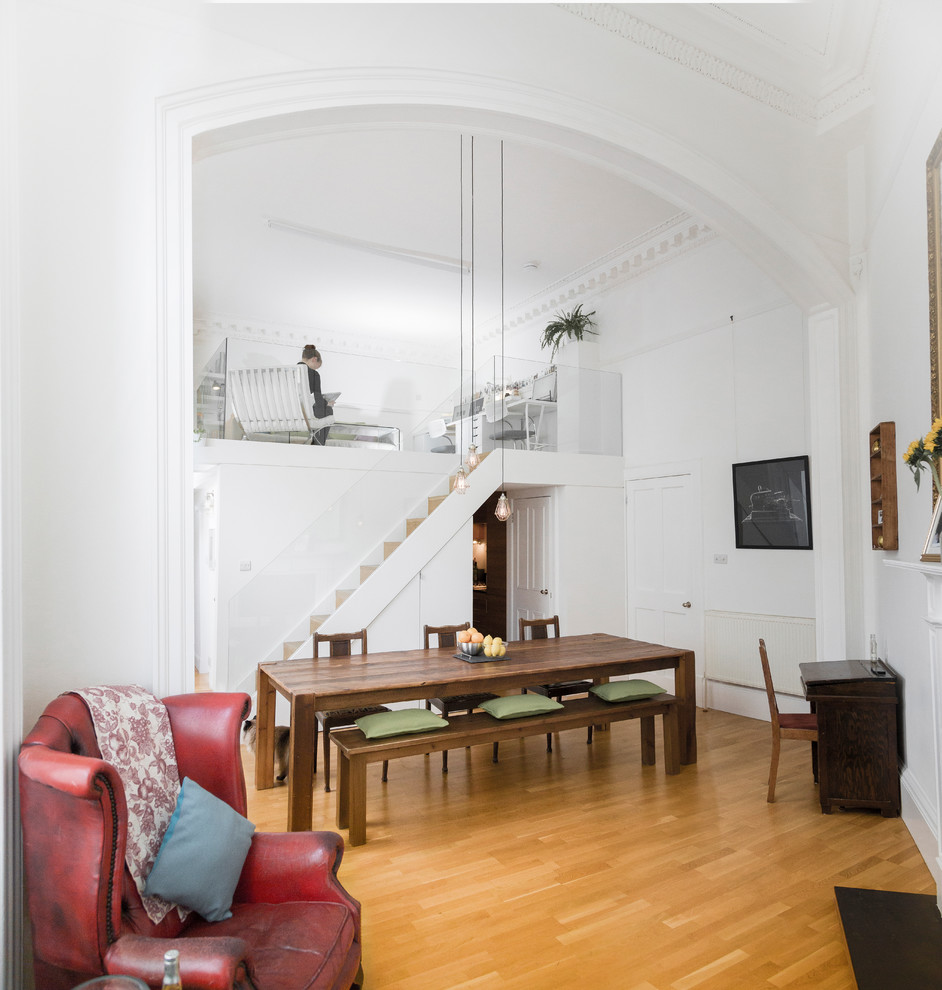 Cette photo montre une petite salle à manger ouverte sur le salon tendance avec un mur blanc, un sol en bois brun et une cheminée standard.