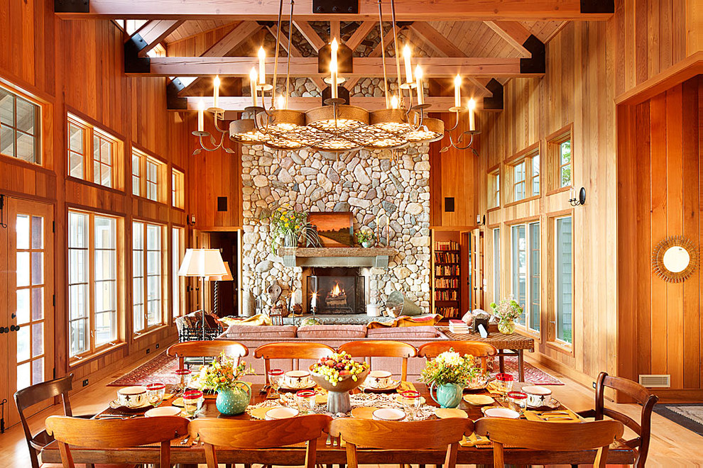 Immagine di una sala da pranzo aperta verso il soggiorno stile rurale con cornice del camino in pietra