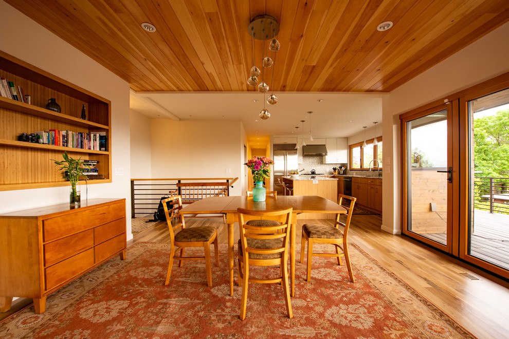 Cette photo montre une salle à manger rétro fermée et de taille moyenne avec un mur beige, parquet clair, une cheminée standard, un manteau de cheminée en pierre, un sol marron et éclairage.