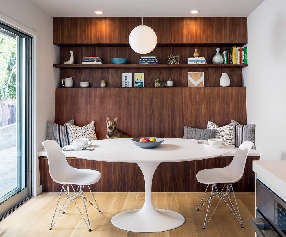 Ispirazione per una sala da pranzo aperta verso la cucina moderna con pareti bianche, parquet chiaro e pavimento beige