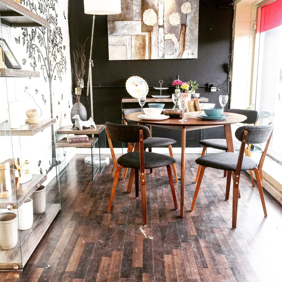 Immagine di una piccola sala da pranzo aperta verso il soggiorno minimalista con pareti nere e pavimento in laminato