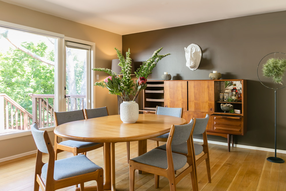 This is an example of a midcentury dining room in San Francisco with grey walls, medium hardwood flooring and feature lighting.