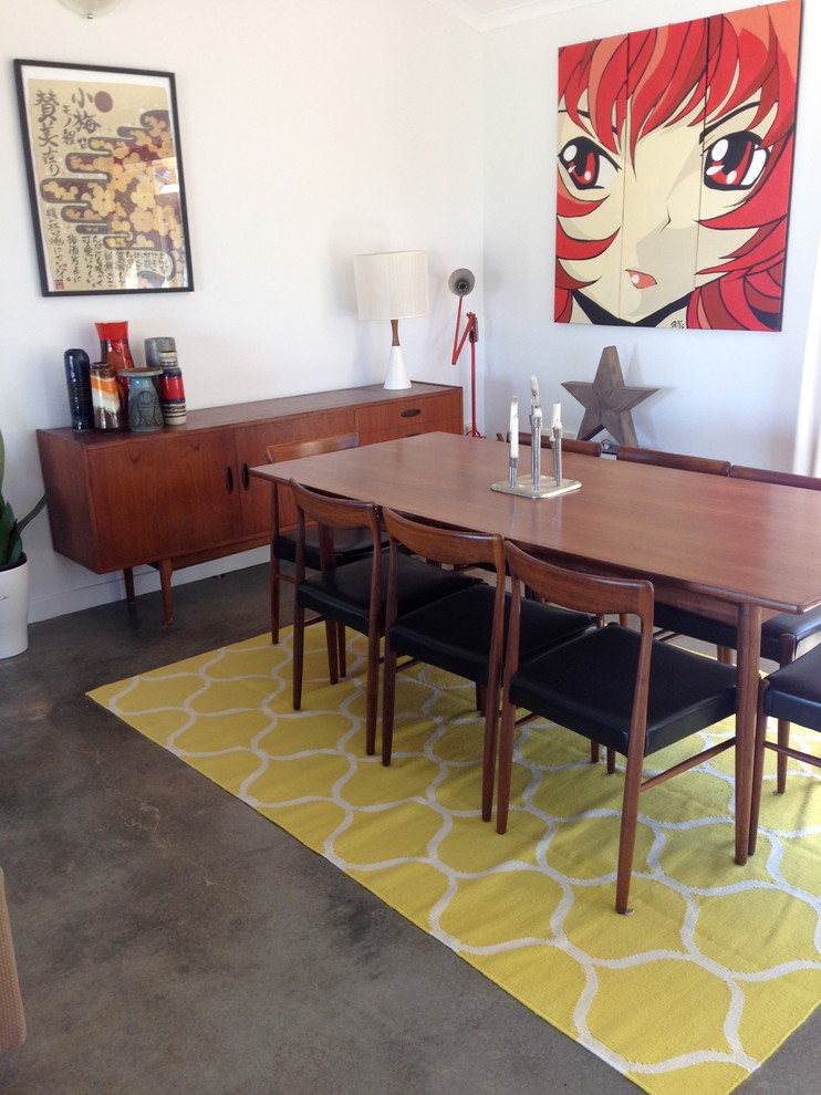 Immagine di una sala da pranzo aperta verso la cucina minimalista con pavimento in cemento