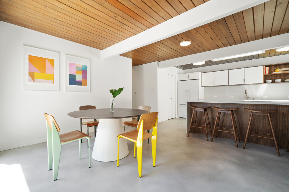 Immagine di una sala da pranzo aperta verso il soggiorno moderna con pareti bianche, pavimento in cemento, pavimento grigio, travi a vista e soffitto in legno