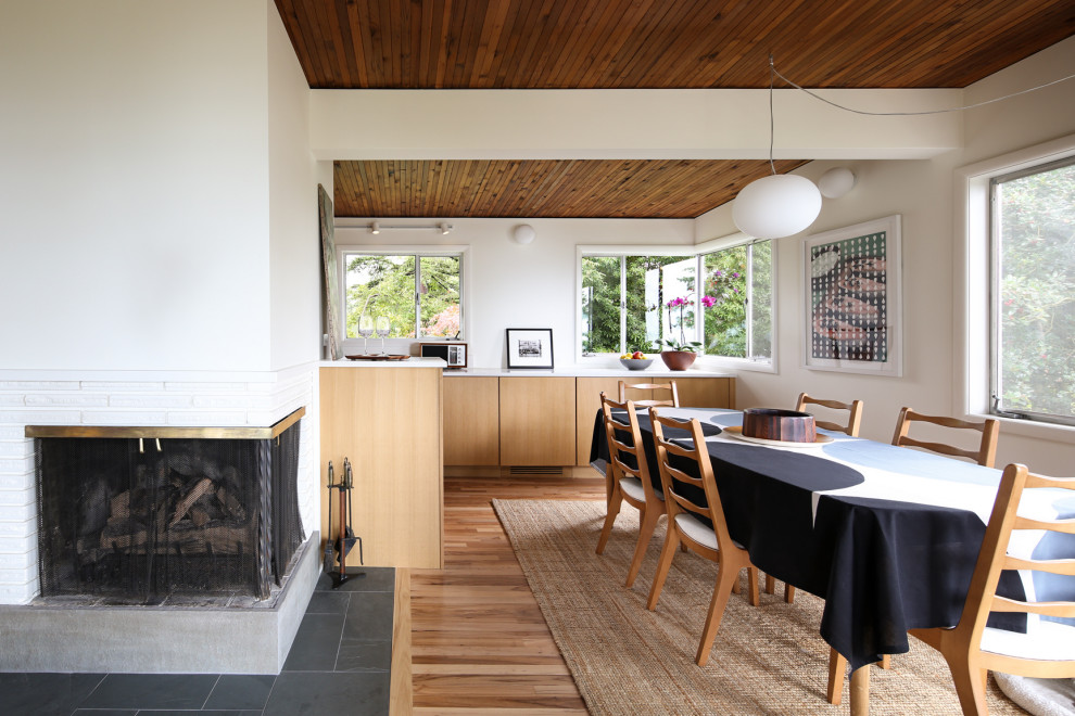 Inspiration för ett mellanstort retro kök med matplats, med vita väggar, en öppen hörnspis, en spiselkrans i tegelsten, mellanmörkt trägolv och brunt golv