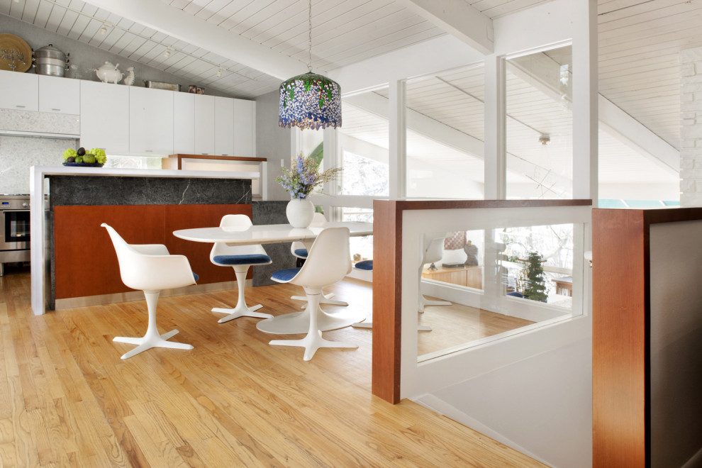 Cette photo montre une petite salle à manger ouverte sur la cuisine rétro avec un mur blanc et un sol en bois brun.